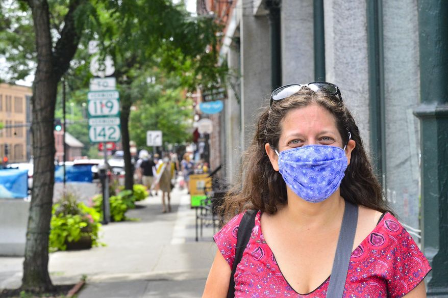 Hilary Francis, Brattleboro town clerk, wears a mask while walking down Main Street, in Brattleboro, Vt., on Friday, July 24, 2020. Vermont Gov. Phil Scott said in a press conference that starting Aug. 1, masks will be mandatory in public. (Kristopher Radder/The Brattleboro Reformer via AP)