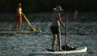 Lindsay Bearup, right, paddles her stand up paddleboard on Soda Lakes at Bear Creek Lake Park on July 21, 2020, in Morrison, Colo. He was at the lake with his mother Valerie Casserini, not pictured. (Helen H. Richardson/The Denver Post via AP)