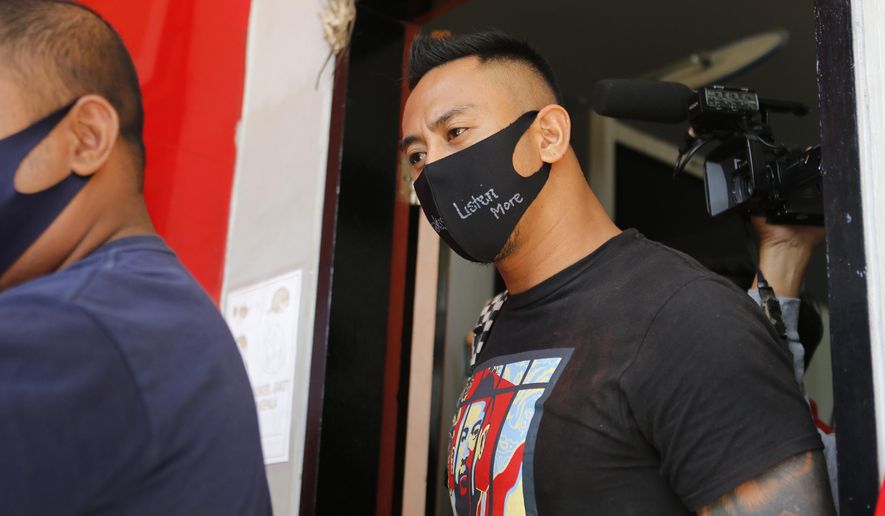 Australian national William Cabantog, right, is escorted by an Indonesian prison guard as he leaves Kerobokan prison in Bali, Indonesia on Saturday, July 25, 2020. Cabantog is released from the prison where he has served to twelve months. Cabantog and another man were arrested last July at the Lost City Club on Indonesia's resort island of Bali with 1.12 grams of cocaine. (AP Photo/Firdia Lisnawati)