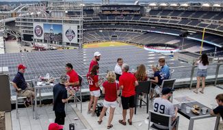People watch the game from the Top of the Yard bar on the rooftop of Hampton Inn &amp;amp; Suites hotel during an opening day baseball game between the New York Yankees and the Washington Nationals at Nationals Park, Thursday, July 23, 2020, in Washington. (AP Photo/Andrew Harnik)