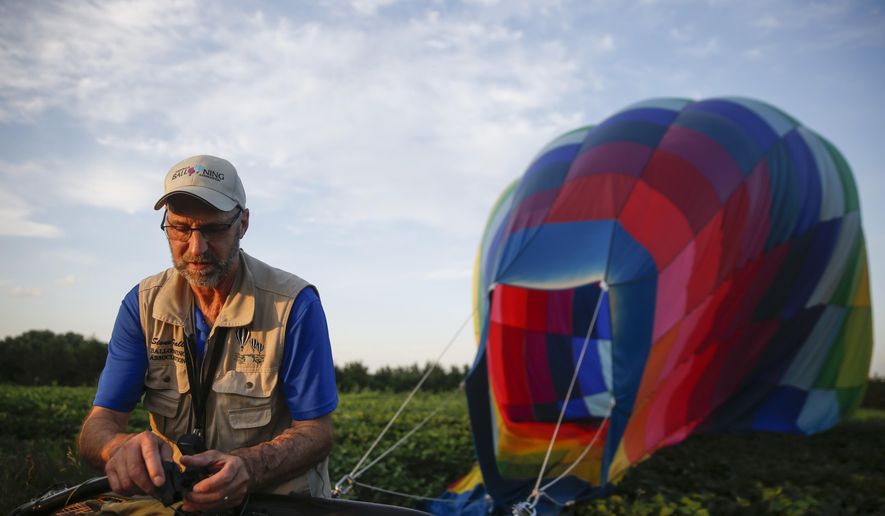 Ron Oppold begins packing up the balloon after landing Thursday, July 9, 2020, southeast of Sioux Falls, S.D. (Abigail Dollins/The Argus Leader via AP)