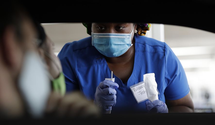Healthcare worker Rahaana Smith instructs passengers how to use a nasal swab, Friday, July 24, 2020, at a drive-thru COVID-19 testing site at the Miami-Dade County Auditorium, in Miami. Florida has experienced a sharp increase in coronavirus deaths over the past two weeks, including another 136 recorded Friday as the state's total confirmed cases topped 400,000. (AP Photo/Wilfredo Lee)