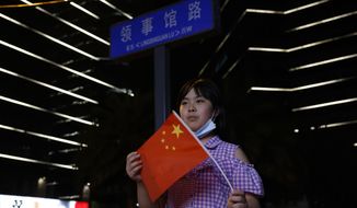 A child holds a Chinese national flag as she poses for a photo near the street sign for Consulate Road outside the United States Consulate in Chengdu in southwest China&#39;s Sichuan province on Sunday, July 26, 2020. China ordered the United States on Friday to close its consulate in the western city of Chengdu, ratcheting up a diplomatic conflict at a time when relations have sunk to their lowest level in decades. (AP Photo/Ng Han Guan)