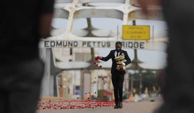 A man places flower petals on the Edmund Pettus Bridge ahead of Rep. John Lewis&#x27; casket crossing during a memorial service for Lewis, Sunday, July 26, 2020, in Selma, Ala. Lewis, who carried the struggle against racial discrimination from Southern battlegrounds of the 1960s to the halls of Congress, died Friday, July 17, 2020. (AP Photo/Brynn Anderson)