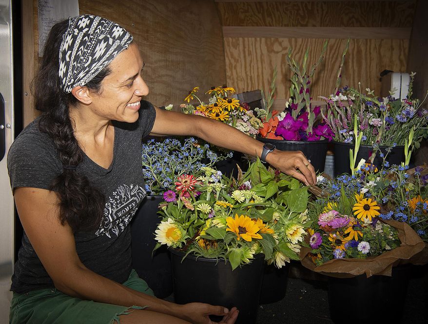 Natasha Bowens Blair sorts buckets of fresh cut flowers in her trailer, July 19, 2020, Frederick, Md. “Pretty much as soon as I stuck my hands into the dirt, and decided I was in love with growing and learning more about plants and the land, there was no way that I could do that without seeing the kind of intersection of race and injustice in our country,” she said. Bowens Blair is co-owner of Native Mountain Farm, which they describe as a “women-owned, Black empowered” business located in Boonsboro, that serves customers in Frederick County. (Bill Green/The Frederick News-Post via AP)