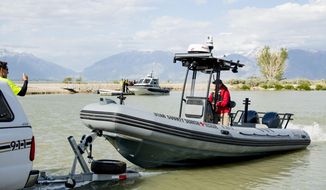 In this May 14, 2020 photo, members of the search team load a boat onto a trailer as authorities examine the body of one of the two Saratoga Springs teenagers that went missing in Utah Lake at the Lincoln Beach Marina west of Spanish Fork, Utah.  The family and friends of two Saratoga Springs teenagers who drowned in Utah Lake after a catastrophic windstorm hit the area in May are proposing building a “life jacket loaner station” to prevent similar accidents from happening in the future.  (Isaac Hale/The Daily Herald via AP)