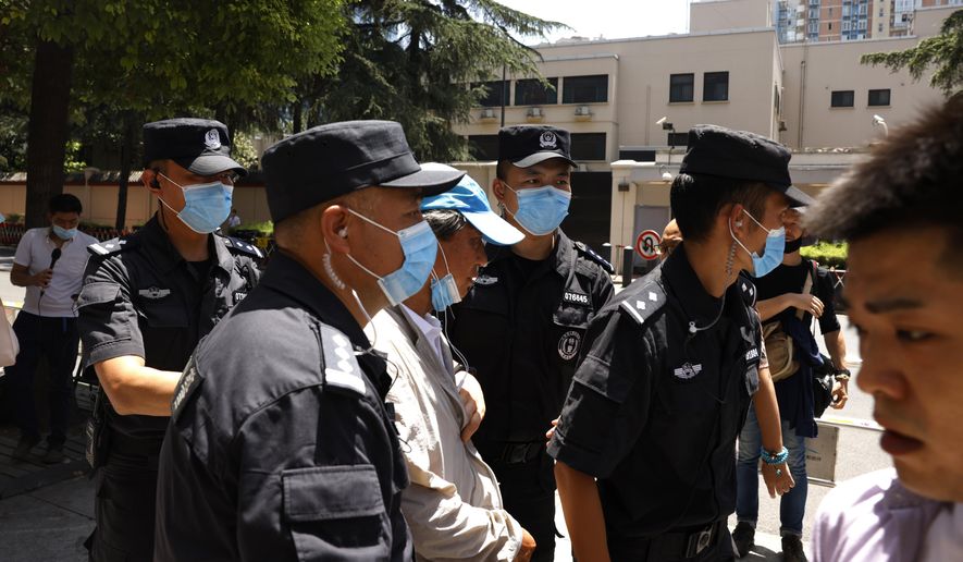 Chinese SWAT police officers escort away a man who tried to show protest slogans on his shirt outside the former United States Consulate in Chengdu in southwest China's Sichuan province on Monday, July 27, 2020. Chinese authorities took control of the former U.S. consulate in the southwestern Chinese city of Chengdu on Monday after it was ordered closed in retaliation for a U.S. order to vacate the Chinese Consulate in Houston. (AP Photo/Ng Han Guan)
