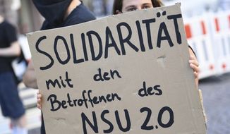 A demonstrator holds a poster with the inscription &#x27;Solidarity with those affected by NSU 2.0&#x27;  during a rally in downtown Wiesbaden, Germany, Tuesday, July 21, 2020. Frankfurt prosecutors said a 63-year-old former police officer and his 55-year-old wife, were detained Friday in the Bavarian town of Landshut in connection threatening mails against several politicians signed &#x27;NSU 2.0.&#x27; (Arne Dedert/dpa via AP)