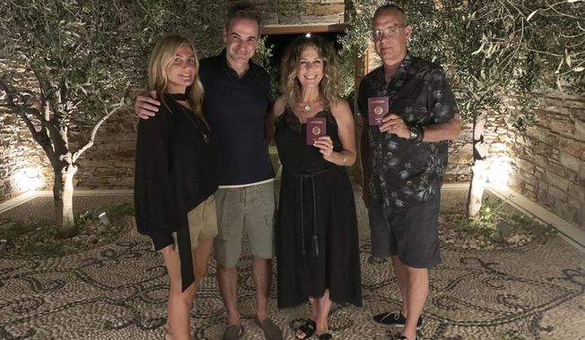 In this photo provided by Greek Prime Minister&#x27;s Office, Greek Prime Minister Kyriakos Mitstotakis, second left, his wife Mareva Grabowski-Mitsotaki, left, pose next to U.S. actor Tom Hanks , right, and his wife Rita Wilson holding up their new Greek passports, in the island of Antiparos, Greece on Saturday, July 25, 2020. Greece offered citizenship Hanks, Wilson, and their two children, in recognition of the family&#x27;s help in assisting victims of a deadly wildfire near Athens in 2018. (Greek Prime Minister&#x27;s Office via AP)