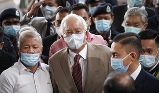 Former Malaysian Prime Minister Najib Razak, center, wearing a face mask with his supporters arrives at courthouse in Kuala Lumpur, Malaysia, Tuesday, July 28, 2020. Najib arrived for a verdict in the first of several corruption trials linked to the multibillion-dollar looting of the 1MDB state investment fund. (AP Photo/Vincent Thian)