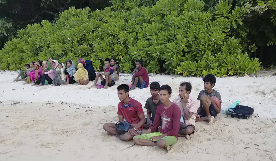 In this photo taken Sunday, July 26, 2020, by the Malaysian Maritime Enforcement Agency, shows rescued Rohingya refugees on a beach on Rebak Island off the resort island of Langkawi, Malaysia. Malaysian authorities say 26 Rohingya refugees, who were feared to have drowned after jumping off their boat off the northern resort island of Langkawi, have been located alive hiding on an islet nearby. (Malaysian Maritime Enforcement Agency via AP)