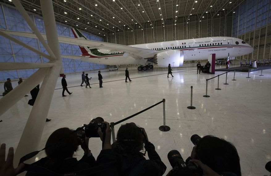 Press photographers cover Mexican President Andres Manuel Lopez Obrador arriving for a press conference in front of the former presidential plane at Benito Juarez International Airport in Mexico City, Monday, July 27, 2020. The president, who only flies commercial as one measure in his austerity government, has been trying to sell the plane since he took office. (AP Photo/Marco Ugarte)