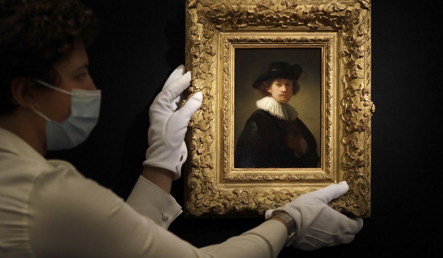 FILE - In this Thursday, July 23, 2020 file photo, a Sotheby's employee adjusts a painting by Rembrandt, entitled 'Self-portrait, wearing a ruff and black hat' at Sotheby's auction rooms in London. The auction house Sotheby’s is holding an online sale featuring artwork that spans five centuries of art history, from Rembrandt to Pablo Picasso and Joan Miró to Banksy. The auction on Tuesday, July 28, 2020, of 70 artworks, from the 17th century to the present day, will be live-streamed from Sotheby's London. The event comes after months of disruption to the art world due to the coronavirus outbreak. (AP Photo/Kirsty Wigglesworth, File)
