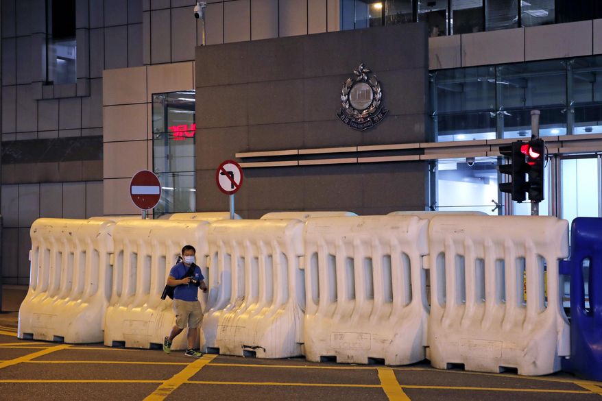 A journalist walks past the police headquarters in Hong Kong, Thursday, July 30, 2020. Hong Kong police have made their first major arrests under a new national security law, detaining four young people on suspicion of inciting secession. Police say they arrested three males and one female, aged 16 to 21, at three locations. All are believed to be students. (AP Photo/Kin Cheung) ** FILE **