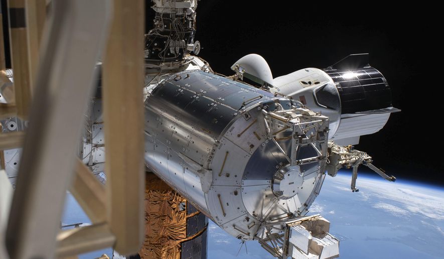 This July 1, 2020 photo made available by NASA shows the SpaceX Crew Dragon, right, docked to the International Space station, during a spacewalk conducted by astronauts Bob Behnken and Chris Cassidy. On Wednesday, July 29, 2020, SpaceX and NASA cleared the Dragon crew capsule to depart the International Space Station and head home after a two-month flight. (NASA via AP)