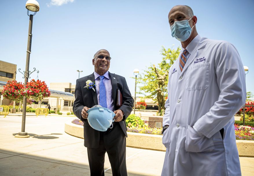Dr. Babu Prasad, right, retired anesthesiologist, is given a hard hat by Dr. Beau Batton, director of newborn services, HSHS St. John's Children's Hospital NICU, after a press conferencing announcing a donation from Prasad of $1,000,000 to the HSHS St. John's Foundation for the St. John's Children's Hospital NICU project at HSHS St. John's Children's Hospital, Thursday, July 23, 2020, in Springfield, Ill. (Justin L. Fowler/The State Journal-Register via AP)