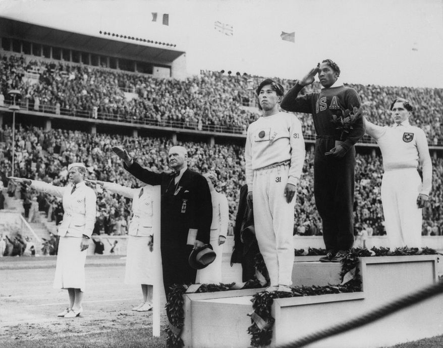 FILE - In this Aug. 11, 1936, file photo, America&#x27;s Jesse Owens, second from right, salutes during the presentation of his gold medal for the long jump, after defeating Nazi Germany&#x27;s Lutz Long, right, during the 1936 Summer Olympics in Berlin. Naoto Tajima of Japan, center, placed third. The performance of Jesse Owens will be honored in the stadium where he won four gold medals at the 1936 Olympic Games when the world championships are held in Berlin this month. (AP Photo/File)