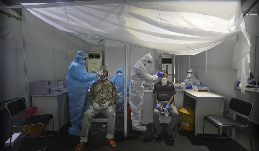 Indian health volunteers take swab samples as part of the India-Israel Non-Invasive Raid COVID-19 test study camp, at a government hospital in New Delhi, India, Friday, July 31, 2020. A team of Israeli scientists are in the country to carry out the final stages of testing of advanced technologies for real time rapid diagnosis of the coronavirus. (AP Photo/Manish Swarup)