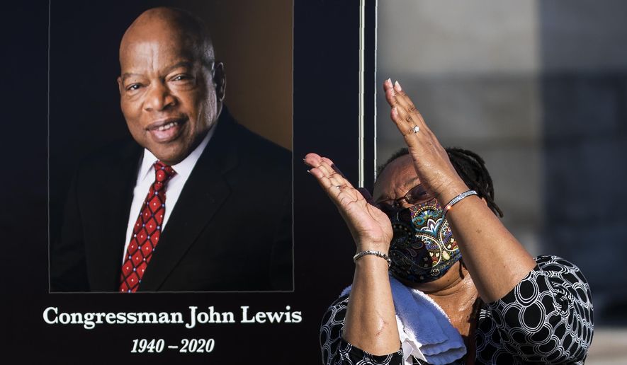 Jaquenette Ferguson from Oxon Hill, Md., gestures as she gets her picture taken beside a portrait of the late Rep. John Lewis, D-Ga., near the East Front Steps of the U.S. the Capitol, Tuesday, July 28, 2020, in Washington. (AP Photo/Manuel Balce Ceneta)