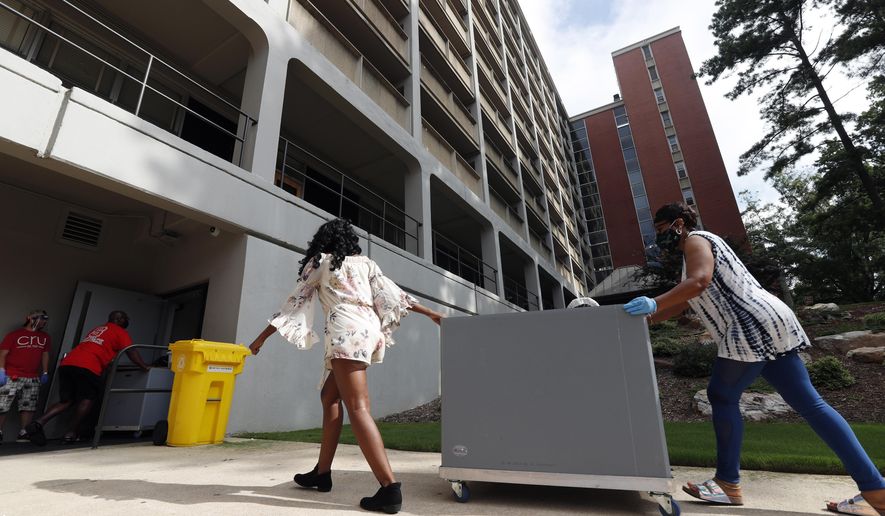 College students begin moving in for the fall semester at N.C. State University in Raleigh, N.C., Friday, July 31, 2020. The first wave of college students returning to their dorms aren’t finding the typical mobs of students and parents. At N.C. State, the return of students was staggered over 10 days and students were greeted Friday by socially distant volunteers donning masks and face shields. . (AP Photo/Gerry Broome)