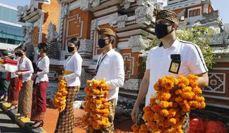 Airport officers wearing face masks line up as they hold flowers to welcome passengers at Bali airport, Indonesia on Friday, July 31, 2020. Indonesia&#39;s resort island of Bali reopened for domestic tourists after months of lockdown due to a new coronavirus. (AP Photo/Firdia Lisnawati)