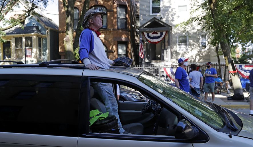 Chicago Cubs fans wait for a ball outside of Wrigley Field before the Opening Day baseball game between the Chicago Cubs and the Milwaukee Brewers in Chicago, Friday, July 24, 2020, in Chicago. In a normal year, that would mean a sellout crowd at Wrigley Field and jammed bars surrounding the famed ballpark. But in a pandemic-shortened season, it figures to be a different atmosphere. (AP Photo/Nam Y. Huh)