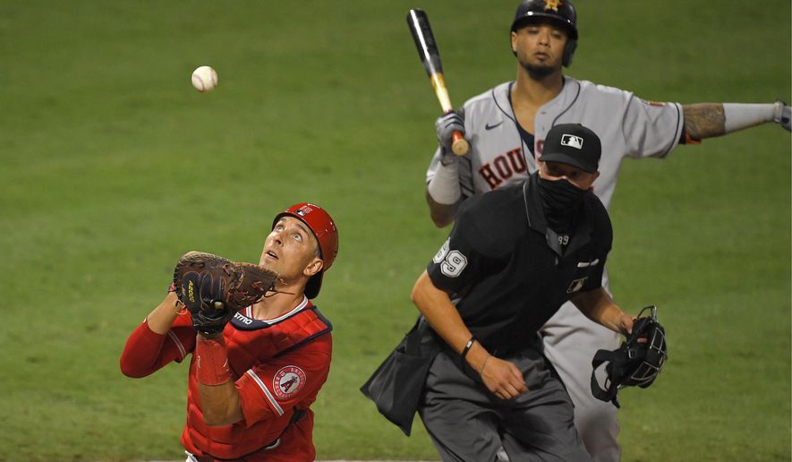 Los Angeles Angels catcher Jason Castro, left, catches a ball that was fouled off the ground by Houston Astros' Martin Maldonado, upper right, as home plate umpire Cory Blaser watches during the ninth inning of a baseball game Friday, July 31, 2020, in Anaheim, Calif. Houston Astros' Myles Straw advanced to second on the play. (AP Photo/Mark J. Terrill)