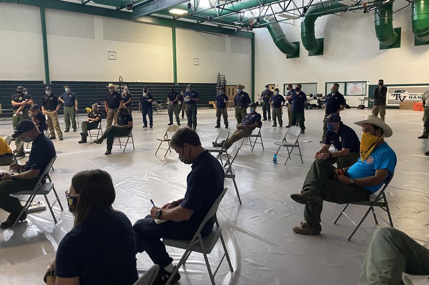 In this July 2020, photo provided by the U.S. Forest Service, wildland firefighters attend a socially distanced briefing at the Smokejumper Depot in Missoula, Mont., before the wildfire season begins. To protect crews from COVID-19 exposure, incident commanders are taking precautions to keep infection risk at a minimum. (U.S. Forest Service via AP)
