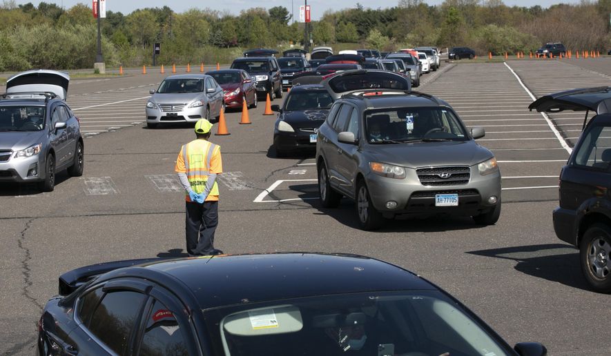 FILE- In this May 7, 2020 file photo, cars line up at a Foodshare distribution center at Rentschler Field in East Hartford, Conn., during the coronavirus pandemic. Officials at the regional food bank have seen an increase in the number of cars arriving at food pick-up locations, such as Rentschler Field in East Hartford, as the extra federal unemployment benefits expire. (AP Photo/Mark Lennihan)