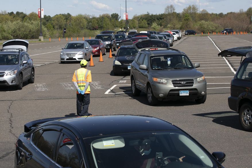 FILE- In this May 7, 2020 file photo, cars line up at a Foodshare distribution center at Rentschler Field in East Hartford, Conn., during the coronavirus pandemic. Officials at the regional food bank have seen an increase in the number of cars arriving at food pick-up locations, such as Rentschler Field in East Hartford, as the extra federal unemployment benefits expire. (AP Photo/Mark Lennihan)