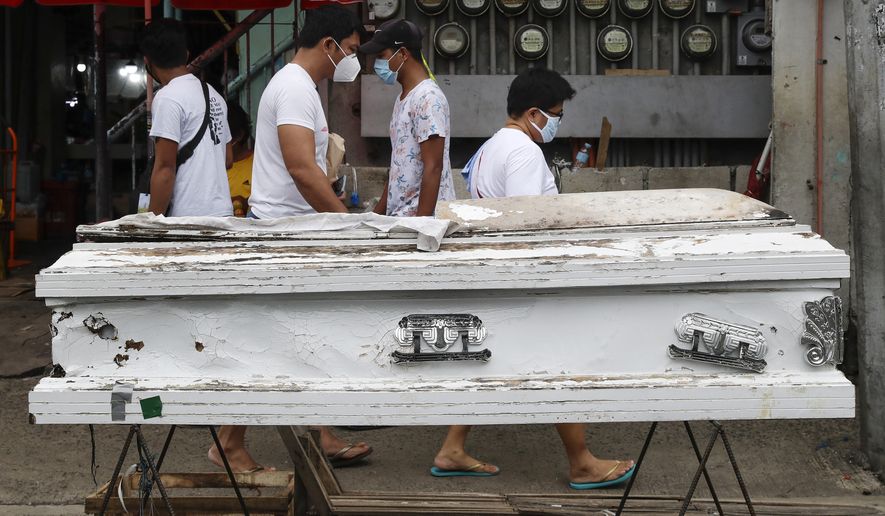 People pass by an empty coffin placed outside a public market to remind people to stay home as the government relaxes quarantine measures against the COVID19 on Sunday, Aug. 2, 2020 in Manila, Philippines. Coronavirus infections in the Philippines continues to surge Sunday as medical groups declared the country was waging &quot;a losing battle&quot; against the contagion and asked the president to reimpose a lockdown in the capital. (AP Photo/Aaron Favila)