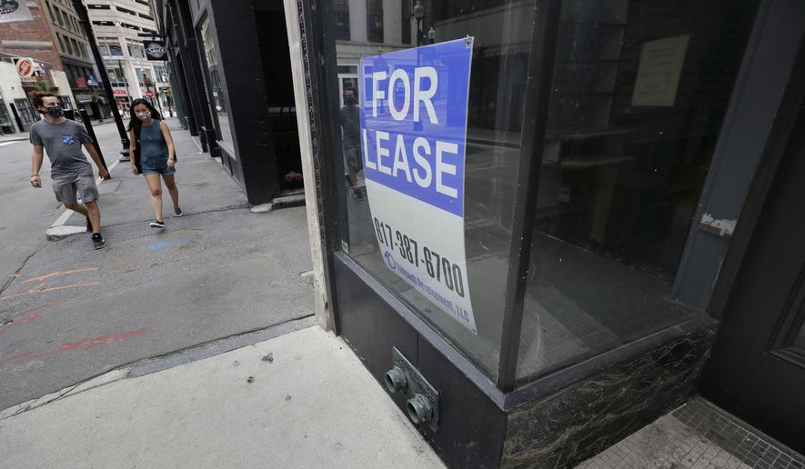 Passers-by wear masks out of concern for the coronavirus as they walk near the glass storefront, right, of an empty business location, in Boston's Downtown Crossing neighborhood, Sunday, Aug. 2, 2020. (AP Photo/Steven Senne)