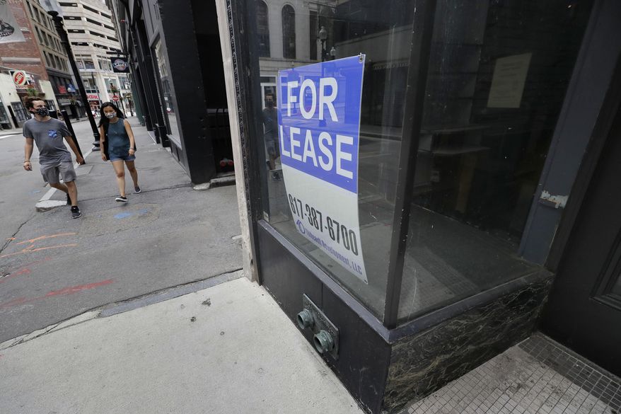 Passers-by wear masks out of concern for the coronavirus as they walk near the glass storefront, right, of an empty business location, in Boston's Downtown Crossing neighborhood, Sunday, Aug. 2, 2020. (AP Photo/Steven Senne)