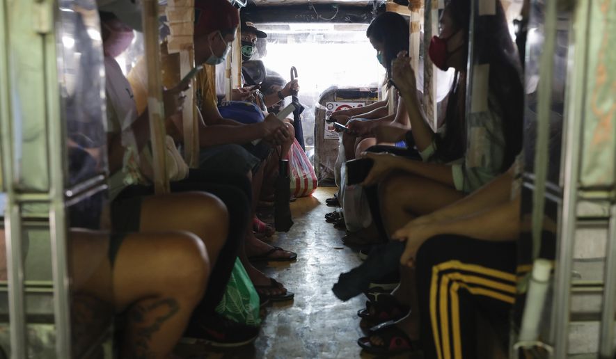 Passengers of a jeepney bus are separated by plastic sheets to help curb the spread of COVID19 as drivers were recently allowed back on the road after months of not being able to work on Sunday, Aug. 2, 2020, in Quezon city, Philippines. Coronavirus infections in the Philippines continues to surge Sunday as medical groups declared the country was waging a losing battle against the contagion and asked the president to reimpose a lockdown in the capital. (AP Photo/Aaron Favila)