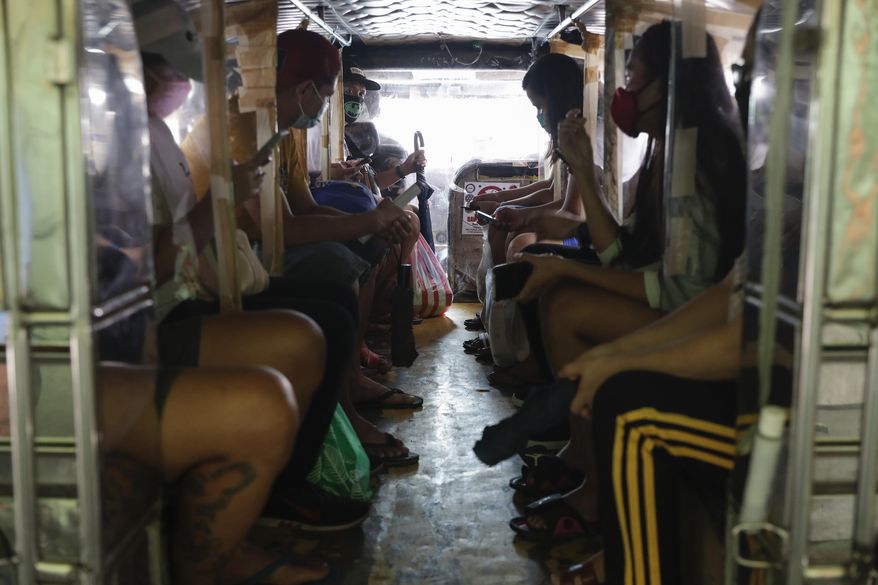 Passengers of a jeepney bus are separated by plastic sheets to help curb the spread of COVID19 as drivers were recently allowed back on the road after months of not being able to work on Sunday, Aug. 2, 2020, in Quezon city, Philippines. Coronavirus infections in the Philippines continues to surge Sunday as medical groups declared the country was waging a losing battle against the contagion and asked the president to reimpose a lockdown in the capital. (AP Photo/Aaron Favila)