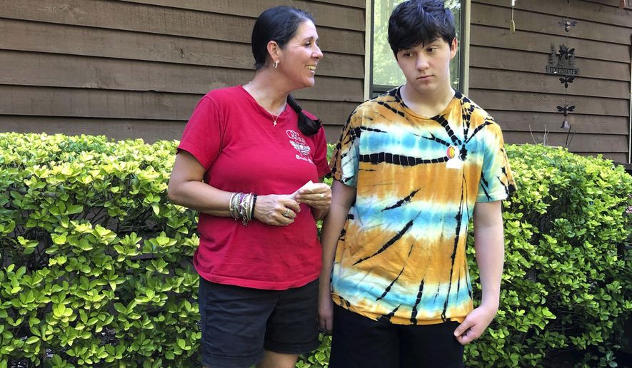 Molly Ball talks to her son Henry about plans to send him back to in-person classes this fall, as they stand outside their house in Woodstock, Ga., Thursday, July 23, 2020. Ball says she thinks Henry and his brother William need the structure and routine of in-person classes, but has regrets about not keeping them home to learn virtually amid the COVID-19 pandemic. Cherokee County, near Atlanta, is one of many districts nationwide that gave parents a choice between in-person and all-online classes this fall. (AP Photo/Jeff Amy)