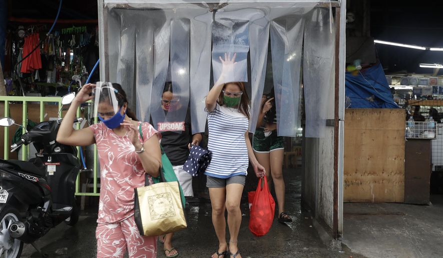 Women exit from a disinfecting area after buying food at a public market in preparation for stricter lockdown measures in Quezon city, Philippines on Monday, Aug. 3, 2020. Philippine President Rodrigo Duterte is reimposing a moderate lockdown in the capital and outlying provinces after medical groups appealed for the move as coronavirus infections surge alarmingly. (AP Photo/Aaron Favila)