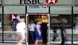 FILE - In this Aug. 28, 2015, file photo, people walk past a branch of HSBC bank in London. Europe’s biggest bank, HSBC, has reported Monday, Aug. 3, 2020, its net profit plummeted 96% in the second quarter of this year as lower interest rates combined with the downturn due to the coronavirus pandemic stunted business activity.  (AP Photo/Frank Augstein, File)