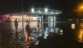 People walk on the flooded Sea Mountain Highway in North Myrtle Beach, S.C., as Isaias neared the Carolinas on Monday night, Aug. 3, 2020. (Jason Lee/The Sun News via AP)
