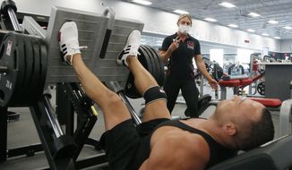 FILE - A trainer and club member at Mountainside Fitness, Thursday, July 2, 2020, in Phoenix, which has challenged Gov. Doug Ducey&#39;s gym shutdown order. A judge heard arguments Monday, Aug. 3, 2020, in the challenge filed by Mountainside Fitness and another health club chain. (AP Photo/Ross D. Franklin, File)