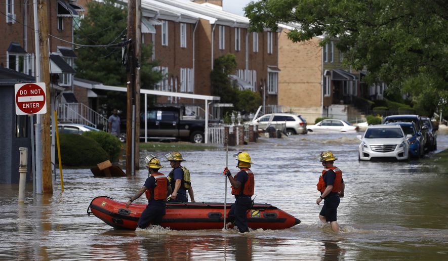 Philadelphia firefighters walk through a flooded neighborhood after Tropical Storm Isaias moved through, Tuesday, Aug. 4, 2020, in Philadelphia. The storm spawned tornadoes and dumped rain during an inland march up the U.S. East Coast after making landfall as a hurricane along the North Carolina coast. (AP Photo/Matt Slocum)