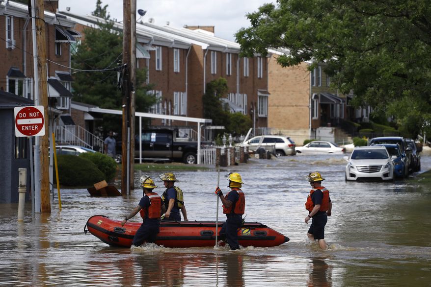 Philadelphia firefighters walk through a flooded neighborhood after Tropical Storm Isaias moved through, Tuesday, Aug. 4, 2020, in Philadelphia. The storm spawned tornadoes and dumped rain during an inland march up the U.S. East Coast after making landfall as a hurricane along the North Carolina coast. (AP Photo/Matt Slocum)