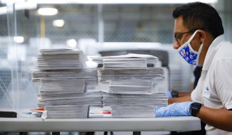 Stacks of ballots are prepared to be checked by a worker at a Board of Elections facility, Wednesday, July 22, 2020, in New York. A federal judge sided with the challenger in a tight New York City Democratic congressional primary and ruled that at least 1,000 disputed ballots should be counted. (AP Photo/John Minchillo)
