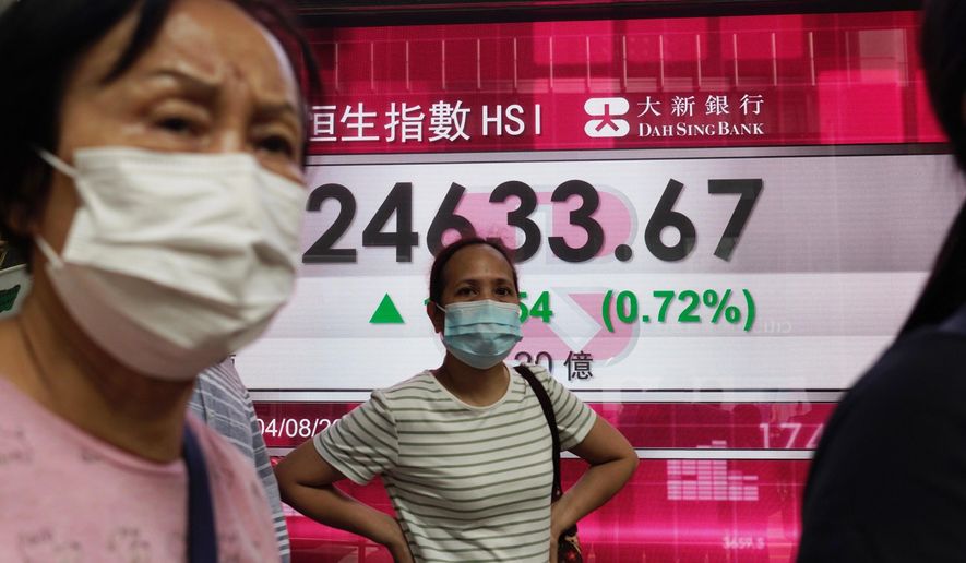 People wearing face masks stand by a bank&#x27;s electronic board showing the Hong Kong share index at Hong Kong Stock Exchange on Tuesday, Aug. 4, 2020. Shares advanced across Asia on Tuesday after Wall Street closed broadly higher on encouraging economic reports, starting off August by closing within 3% of the record high it set in February. (AP Photo/Vincent Yu)