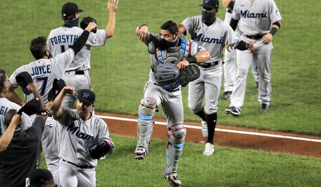 Miami Marlins catcher Francisco Cervelli, center, reacts he engages with teammates in a social distant celebration after defeating the Baltimore Orioles 4-0 during a baseball game, Tuesday, Aug. 4, 2020, in Baltimore. (AP Photo/Julio Cortez)