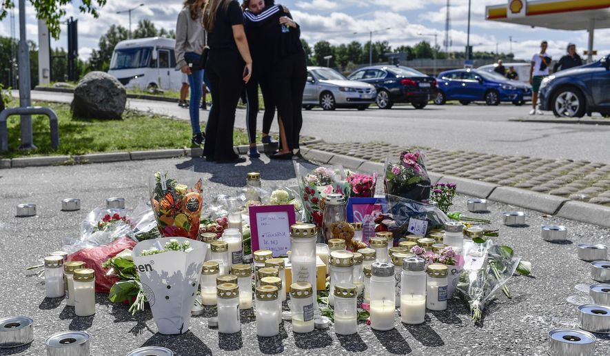 People gather near to where a twelve-year-old girl was shot and killed near a petrol station in Botkyrka, south of Stockholm, Sweden, Monday Aug. 3, 2020. (Stina Stjernkvist/TT via AP)