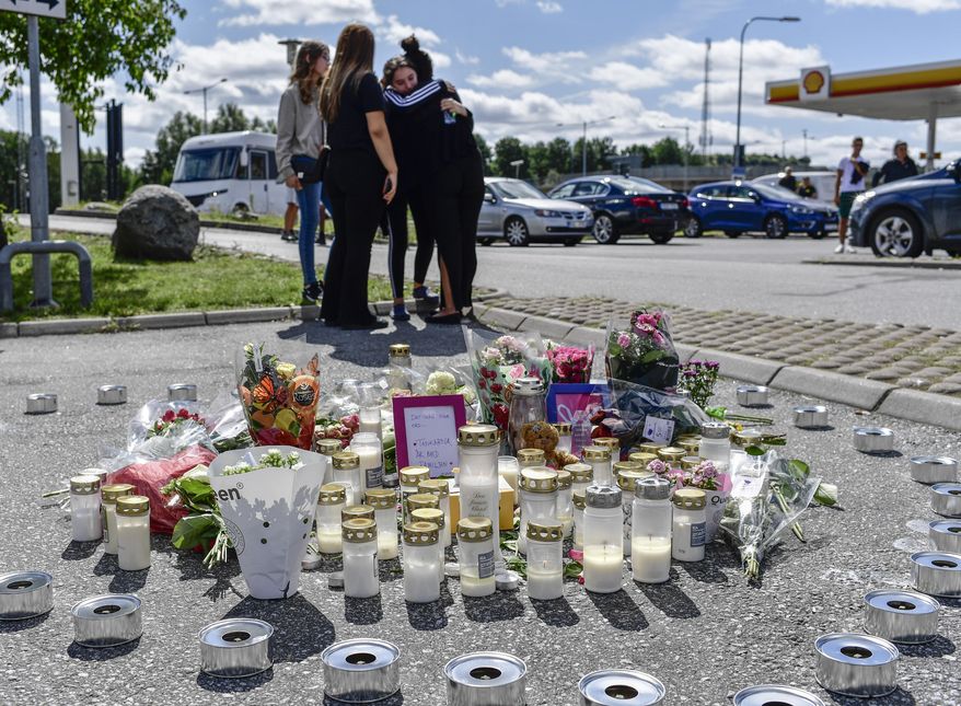 People gather near to where a twelve-year-old girl was shot and killed near a petrol station in Botkyrka, south of Stockholm, Sweden, Monday Aug. 3, 2020. (Stina Stjernkvist/TT via AP)