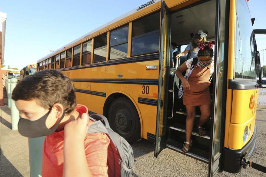 Corinth Elementary School students exit their bus wearing masks to protect against coronavirus, as they arrive for their first day back to school on Monday, July 27, 2020 in Corinth, Miss. (Adam Robison/The Northeast Mississippi Daily Journal via AP)