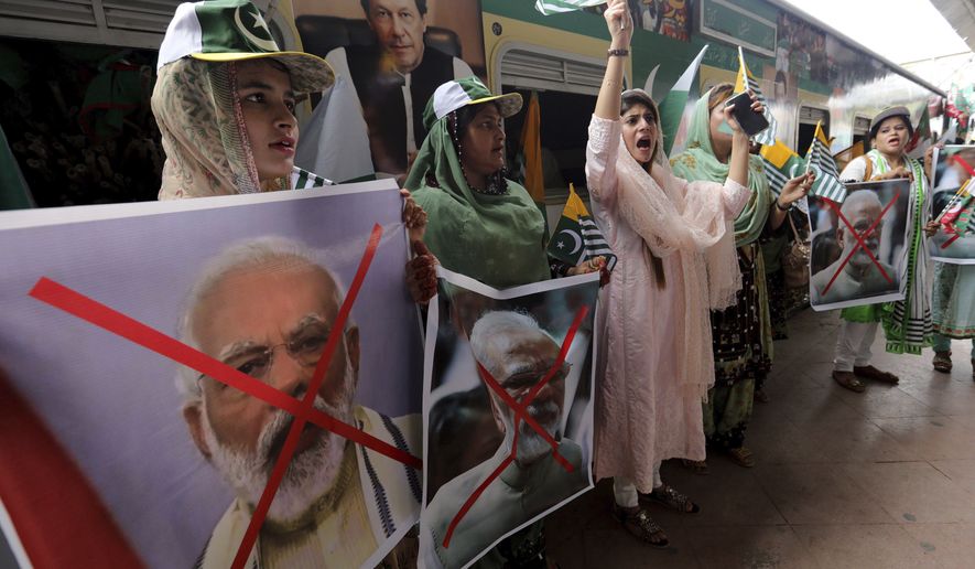 Women hold crossed out portrait of Indian Prime Minister Narendra Modi as they participate in a train march to mark the first anniversary of India&#x27;s decision to revoke the disputed region&#x27;s semi-autonomy, in Karachi, Pakistan, Wednesday, Aug. 5, 2020. Last year on Aug. 5, India&#x27;s Hindu-nationalist-led government of Prime Minister Modi scrapped its separate constitution and removed inherited protections on land and jobs. (AP Photo/Fareed Khan)