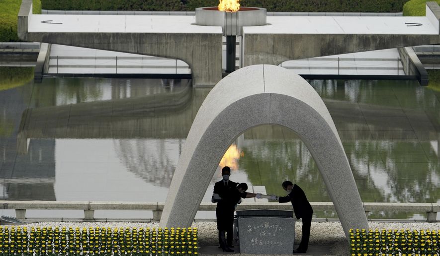 Kazumi Matsui, right, mayor of Hiroshima, and the family of the deceased bow before they place the victims list of the Atomic Bomb at Hiroshima Memorial Cenotaph during the ceremony to mark the 75th anniversary of the bombing at the Hiroshima Peace Memorial Park Thursday, Aug. 6, 2020, in Hiroshima, western Japan. (AP Photo/Eugene Hoshiko)